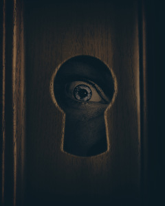 Eye looking through door keyhole