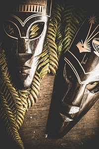 Tribal Masks With Ferns On Wooden Table